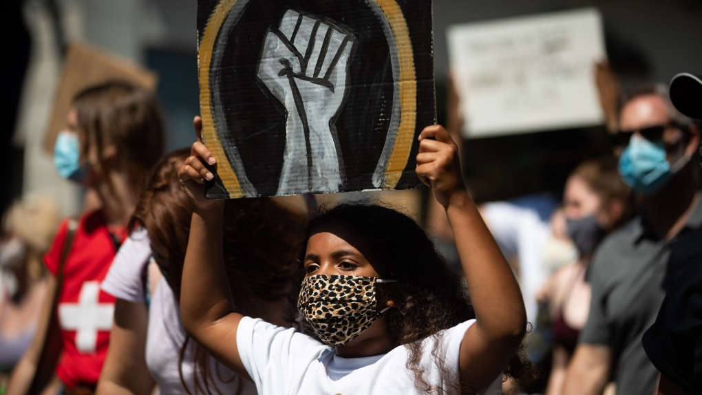 A young girl holds up a sign as she marches with hundreds of others during an Emancipation Day March, in Vancouver