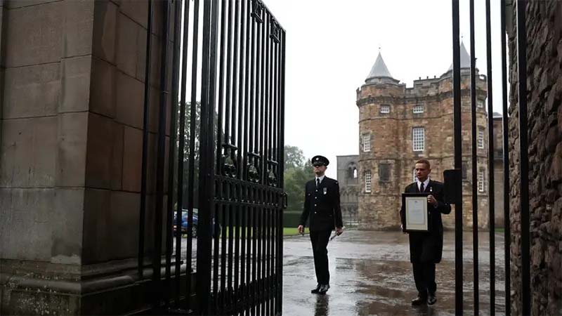 Personnel holds an announcement of the death of Queen Elizabeth, outside the Palace of Holyroodhouse, in Holyrood, Edinburgh